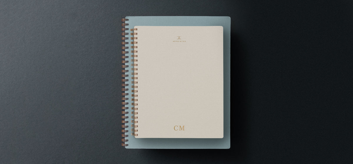 A 2022 planner sits atop a gray gift box agains a dark gray gradient background